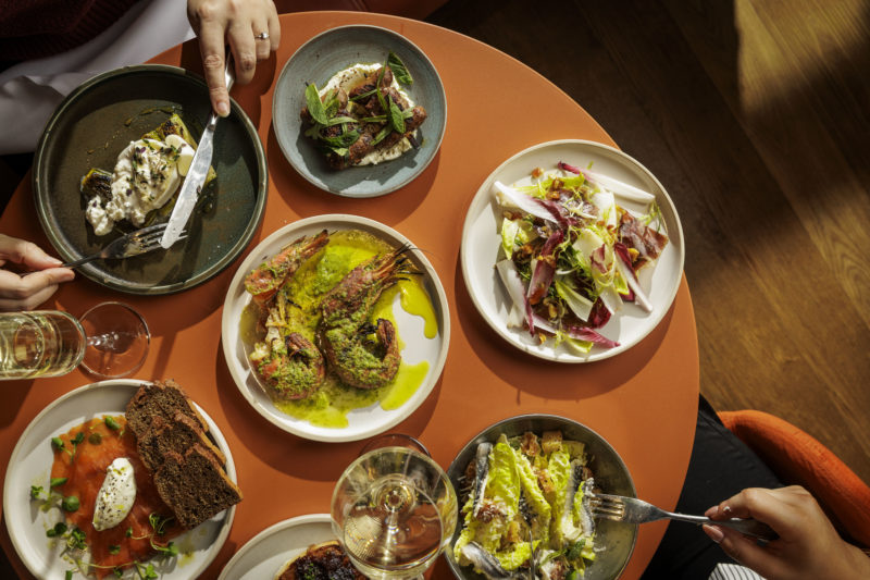 Top down view of a table with multiple plates of food to share