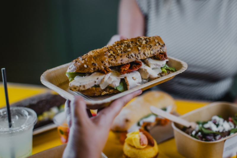 Server is handing a customer a plate with a sandwich